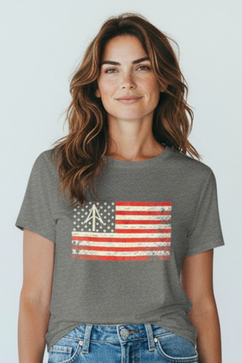 Person wearing a blue t-shirt with an American flag design on a plain background
